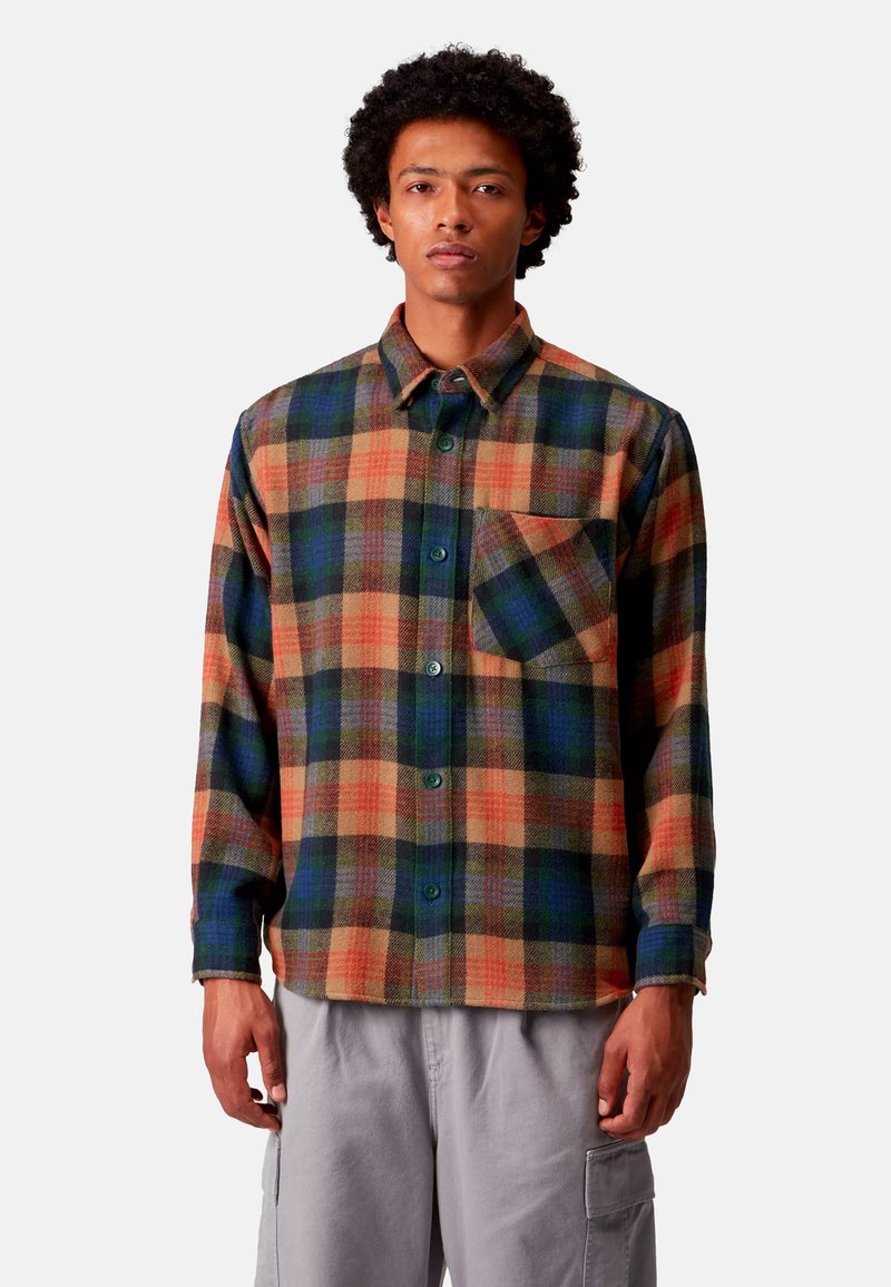 Camicia di flanella a quadri con quadrati verdi, arancioni e blu scuro, dotata di bottone frontale, taschino sul petto e vestibilità rilassata. Texture morbida.
