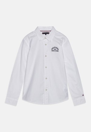 Weißes Baumwollhemd mit Knöpfen und langen Ärmeln, mit Kragen, versehen mit dem marineblauen, bestickten Logo "HILFIGER 1985 NEW YORK" und dezenten Logodetails an den Ärmeln.