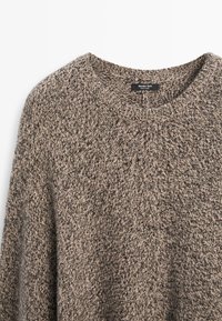 Maglione marrone e beige a maglia con scollo rotondo, motivo testurizzato e etichetta all'interno vicino al colletto.