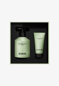 Groene plastic pompflacon met het label "Soul & Body Lotion" en een groene tube met het label "Soul & Body Wash," beide in een zwarte doos met een lichtgroene buitenkant.