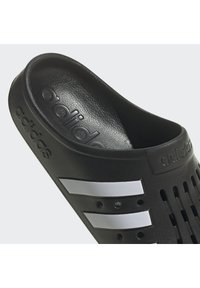 Infradito neri con finitura testurizzata, design aperto sulla punta, tre distintive strisce bianche e dettagli perforati per la traspirabilità.