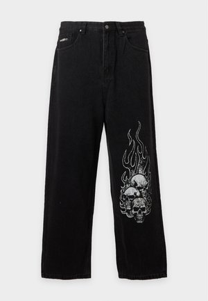 Jeans pretos de perna larga com cintura alta e fecho de botões, com um gráfico branco de três caveiras rodeadas por chamas na perna direita.