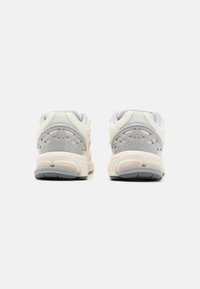 Des chaussures de sport blanches et gris clair avec un dessus texturé, un col rembourré et une semelle rembourrée accentuée de gris clair.