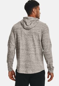 Sudadera de manga larga gris heather con una textura suave, capucha ajustable y un dobladillo redondeado. La tela presenta un patrón jaspeado sutil.