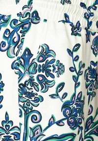 Tela con estampado floral que presenta diseños en espiral en azul, verde y rosa sobre un fondo color crema; textura suave con una cinturilla elástica.