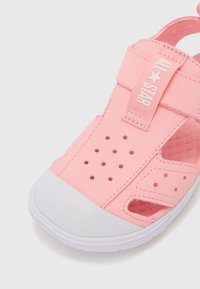 Růžová syntetická sandal s ventilačními otvory, bílou gumovou špičkou, nastavitelním popruhem a texturovanou stélkou pro pohodlí.