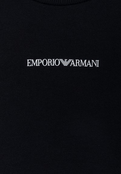 Μαύρη μπλούζα με κουκούλα με το λευκό κείμενο "EMPORIO ARMANI" σε έντονη, μοντέρνα γραμματοσειρά τοποθετημένη κεντρικά στο στήθος. Λείο υλικό.