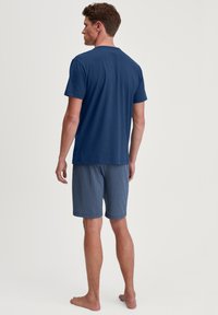 Navyblauwe katoenen t-shirt met korte mouwen gecombineerd met een geblokte korte broek met een geometrisch patroon in donkere blauwtinten.