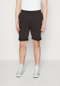 Shorts en coton noir avec taille à cordon de serrage, ourlets retroussés et poches latérales, associés à des baskets montantes bleu clair.