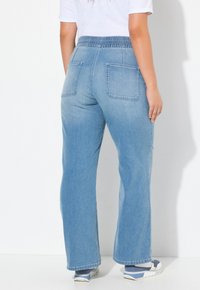 Ljust blå denimjeans med en avslappnad passform, elastisk midja, två bakfickor och en rak bendesign. Bärs med vita och blå sneakers.