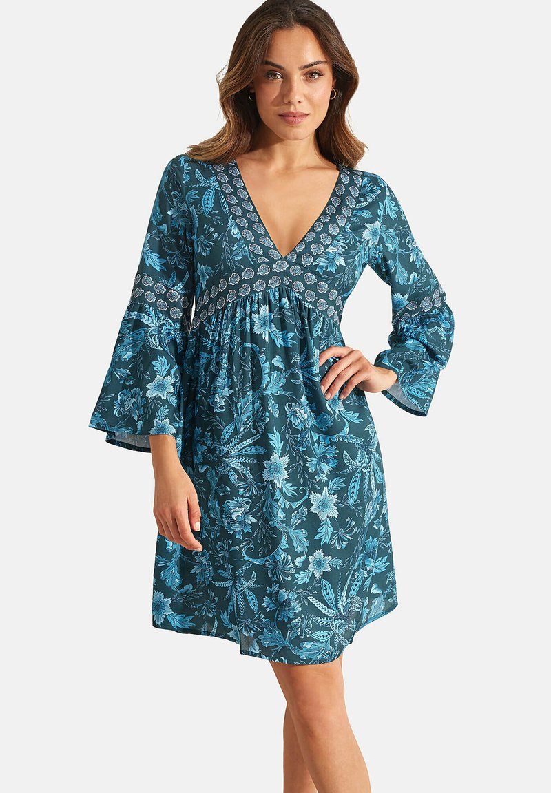 Robe florale bicolore avec un décolleté en V profond, des manches évasées et une taille empire. Fabriquée en tissu léger, elle présente des motifs floraux bleus délicats.