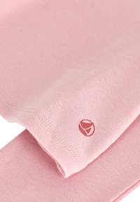 Helles rosa Baumwollgewebe mit einer glatten Textur, versehen mit einem kleinen roten Logo. Die Kanten sind ordentlich genäht.