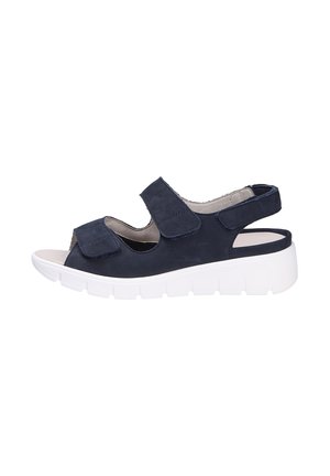Sandal in suede blu scuro con cinturini in velcro, punta aperta, soletta imbottita e suola piatta bianca con scanalature orizzontali.
