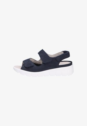 Sandal in suede blu scuro con cinturini in velcro, punta aperta, soletta imbottita e suola piatta bianca con scanalature orizzontali.