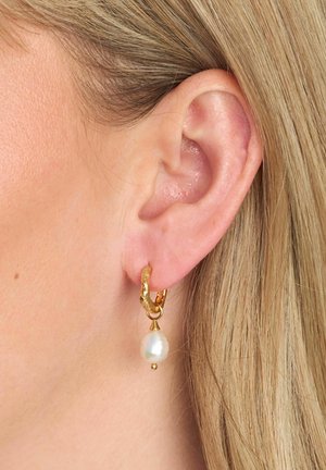 Orecchini a cerchio in oro con design testurizzato, perla d'acqua dolce pendente e piccolo dettaglio dorato nella parte inferiore.