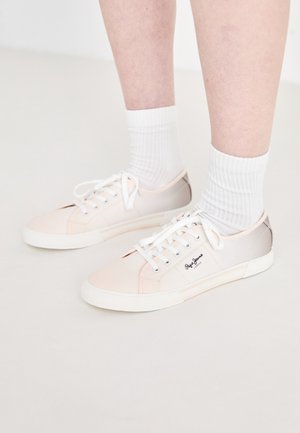 Gaišas auduma kedas ar baltām mežģīnēm, kurām ir rozā un bežīgas akcenti, baltā gumijas zole un logo sānos.