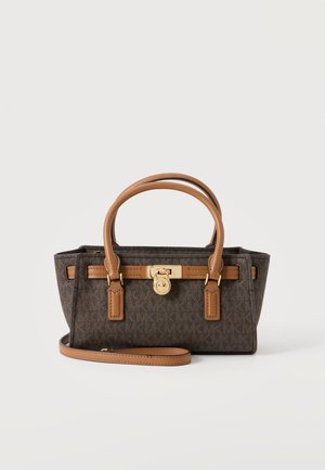 Petit sac à main rectangulaire marron de créateur avec doubles poignées couleur camel, détail de verrou doré et bandoulière amovible sur fond blanc.