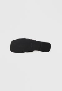 Czarna sandałka z kwadratowym noskiem, płaską podeszwą i gładkim wykończeniem. Charakteryzuje się prostym wzornictwem, idealna do codziennego noszenia.