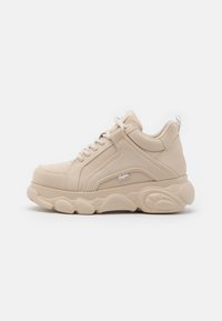 Beige höga sneakers med en strukturerad, slät ovandel, framträdande snörning och en kraftig sula med ett vågformat mönster.