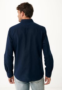 Navyblauwe blouse met lange mouwen, een klassieke kraag, knoopmanchetten en een gebogen zoom. Gemaakt van zachte, lichte stof.