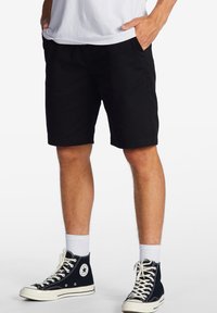 Pantaloni corti neri realizzati in un morbido cotone misto, con un taglio classico e tasche laterali, abbinati a sneakers alte nere e calze bianche.