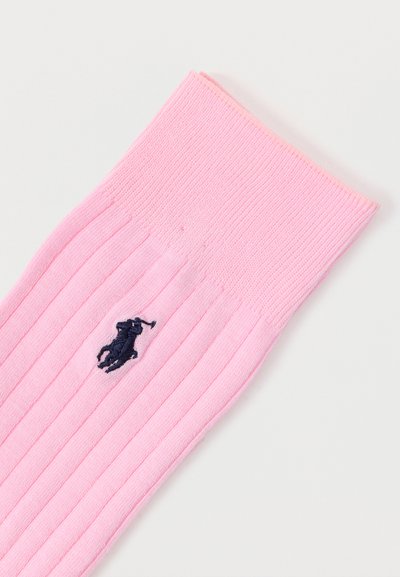 Pink gerippte Socke mit einem marineblauen, gestickten Polo-Spieler-Logo nahe der oberen Manschette auf weißem Hintergrund.