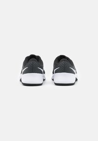 Scarpe da corsa nere con una tomaia grigia testurizzata, dettagli bianchi e un design distintivo del tallone. Suola in gomma per la trazione.