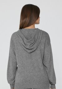 Grauer Kapuzenpulli aus weichem, strukturiertem Stoff. Mit lockerer Passform, langen Ärmeln sowie gerippten Bündchen und Saum.