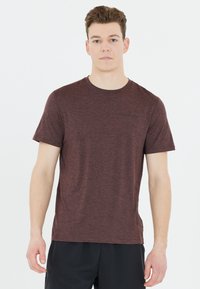 Maroon lyhytnukkainen t-paita teksturoitua kangasta. Ominaisuuksia pyöreä kaula-aukko ja pieni musta logo edessä, yhdistettynä tummiin shortsiiin.