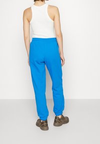 Blå bomullssweatpants med elastisk midja och muddar, kombinerat med en vit tanktop. Texturerad tyg med avslappnad passform.