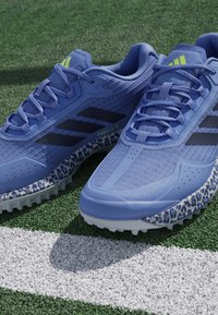 Blue athletic shoes with textured upper, black stripes, and leopard print accents on the sole. Features lace-up design and padded collar.