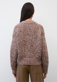 Hrubě pletený svetr v tlumených růžových a hnědých tónech. Má kulatý výstřih a žebrovaný lem, s volným střihem a spadlými rameny.