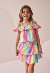Färgglad, flerstegs klänning med ett pastellregnbågsmönster. Axelbandslös design med volangkanter och justerbara axelremmar.