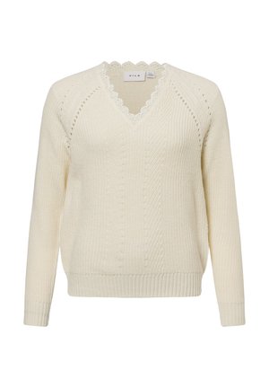 Suéter crema de punto con escote en V, bordes con ondas, puños y dobladillo acanalados. Presenta patrones de textura intrincados y mangas raglán.