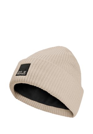 Beige gebreide muts met zwarte binnenvoering en een zwart vierkant patch met het Jack Wolfskin-logo op de omslag.