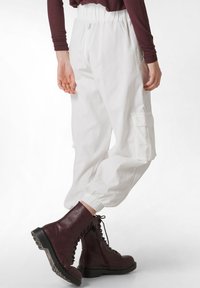Witte cargobroek met een trekkoord in de taille, elastische boorden en zakken. Gecombineerd met bordeauxrode veterschoenen met een robuuste zool.