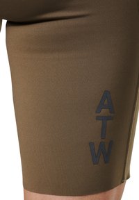Bruine sportieve shorts gemaakt van rekbaar materiaal; voorzien van een zwart "ATW" logo en contrasterende stiksel langs de zijkant voor extra detail.