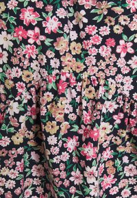 Tissu noir avec un motif floral comprenant des fleurs roses, blanches et jaunes. Comprend des détails froncés pour la texture et la variation de design.