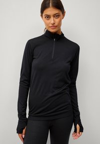 Zwarte langärmige rits-top met hoge kraag, aansluitend ontwerp en duimgaten bij de manchetten voor extra comfort en bedekking.