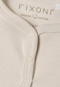 Hellbeige Bodysuit aus Bio-Baumwolle mit rundem Kragen, ausgestattet mit zwei Druckknöpfen und sichtbaren Nähdetails. Der Markenname ist innen aufgedruckt.