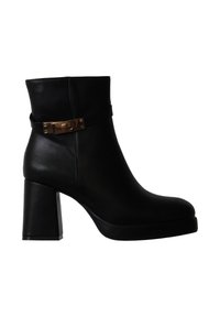 Bottine noire en cuir avec un talon bloc et une bride à boucle rectangulaire dorée autour de la cheville.
