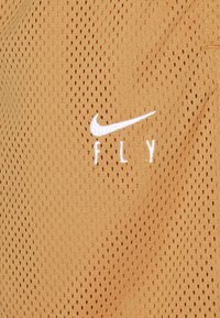 Ropa deportiva Nike en tela de malla beige, con perforaciones transpirables y logo bordado en blanco con la palabra "FLY".