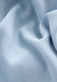 Tela azul claro con una textura suave, que muestra pliegues y arrugas delicadas, exhibiendo un brillo sutil y un patrón de tejido fino.