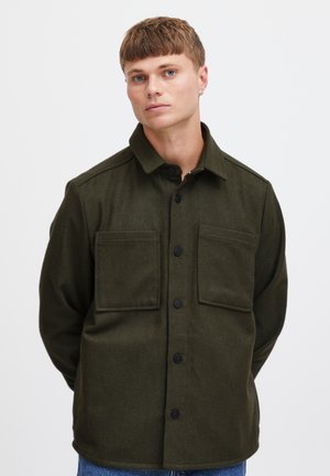Camicia verde oliva con bottoni, realizzata in un tessuto testurizzato, dotata di colletto a punta, due tasche sul petto e bottoni neri, progettata con una vestibilità rilassata.