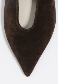 Zapato marrón de ante con punta afilada y un diseño de corte. Textura suave y acabado liso. Presenta una silueta elegante para un diseño minimalista.