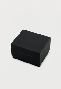 Črni pravokotni škatli z mat teksturo, z vtisnjenimi črkami "A/X" na vrhu in napisom "ARMANI EXCHANGE" spredaj.