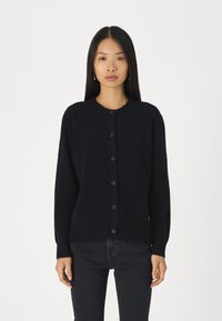 Černý button-down kardigan vyrobený z měkké, texturované látky. Má dlouhé rukávy, kulatý výstřih a pět odpovídajících knoflíků vpředu.