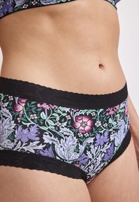 Mutande a vita alta con motivo floreale, caratterizzate da pizzo nero lungo la vita e le aperture delle gambe, con fiori multicolore su uno sfondo scuro.