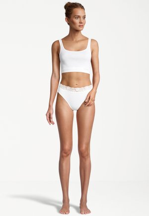 Weißes Baumwoll-Crop-Top mit breiten Trägern und passenden weißen Bikini-Unterteilen, die einen Spitzenrand am Taillenbund haben. Glatte Textur und figurbetontes Design.