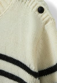 Weißer Strickpullover mit schwarzen horizontalen Streifen, einem V-Ausschnitt und einem dekorativen schwarzen Knopf an der Schulter.